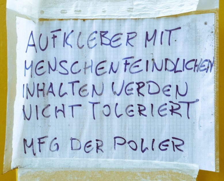 Flugblatt mit Text: "Aufkleber mit menschenfeindlichen Inhalten werden nicht toleriert. MFG, der Polier